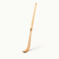 A single light natural wood ski or snowboard blank standing upright on a clean off-white background.